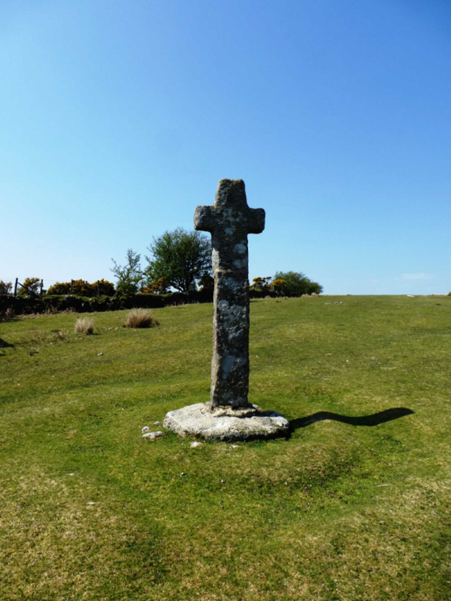 A restored stone cross on a grass hill